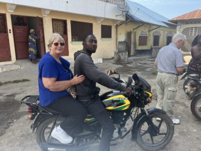 A UK volunteer sitting on a local motorbike taxi